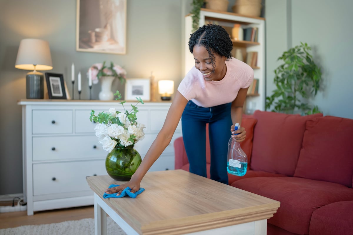 Limpieza de la mesa de un salón en una vivienda con paño y spray